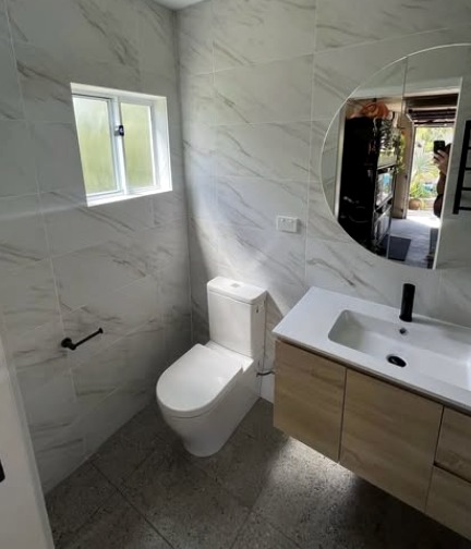 Bathroom with marble-look tiles, timber vanity and round mirror