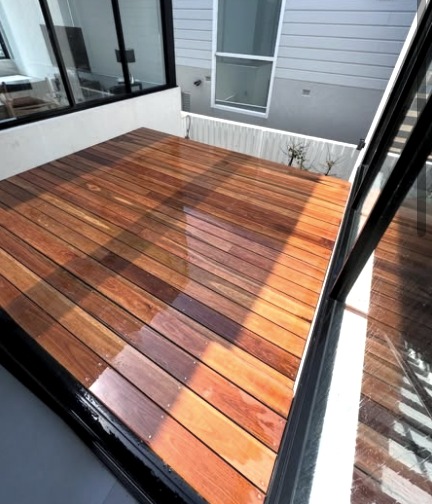 Hardwood deck with fresh oil finish beside glass doors
